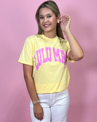 Woman wearing a yellow t-shirt with pink text against a pink background