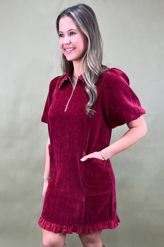 Woman wearing a burgundy dress with short sleeves against a plain background
