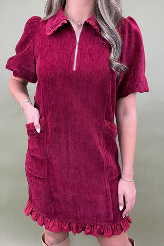 Red dress with puff sleeves and ruffled details on a plain background