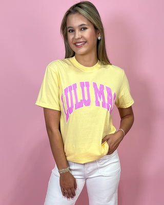 Woman wearing a yellow t-shirt with pink text against a pink background