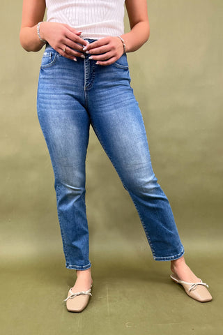 Person wearing blue jeans and a white top on a green background