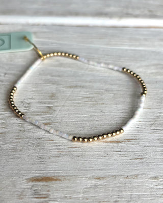 Gold beaded bracelet on a light wooden surface