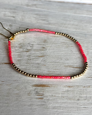 Bracelet with pink and gold beads on a wooden surface