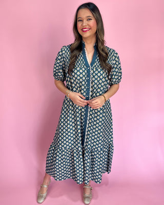 Woman wearing a patterned dress against a pink background