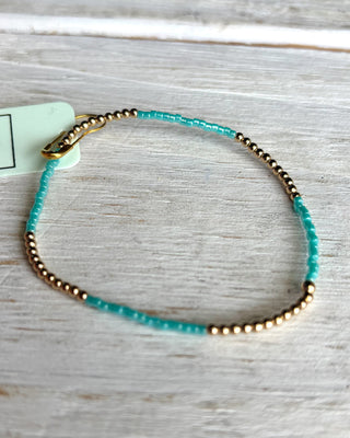 Bracelet with gold and turquoise beads on a wooden surface