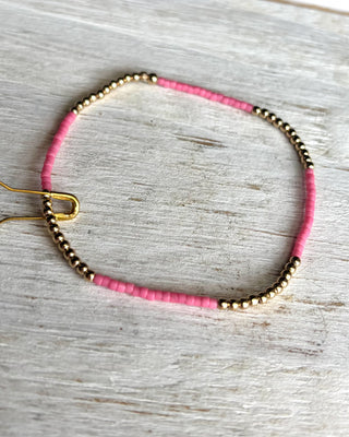 Bracelet with pink and gold beads on a light wooden surface