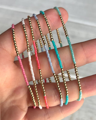 Set of colorful beaded bracelets on a hand against a neutral background