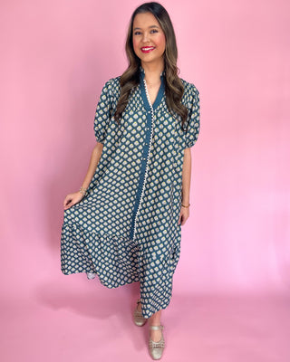 Woman wearing a blue and white patterned dress on a pink background