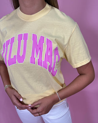Person wearing a yellow t-shirt with pink text on a pink background