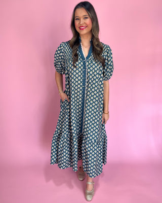 Woman wearing a patterned dress against a pink background