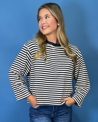 A woman wearing a black and white horizontally striped long-sleeve top with a crew neck, paired with blue jeans