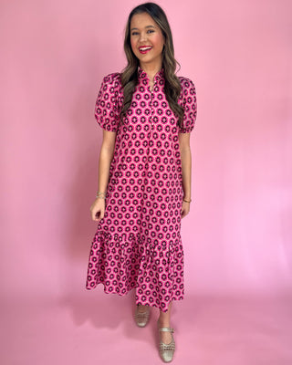 Woman wearing a pink patterned dress against a pink background