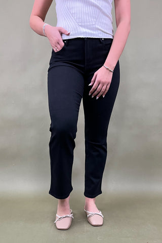 Person wearing black pants and a white top against a plain background