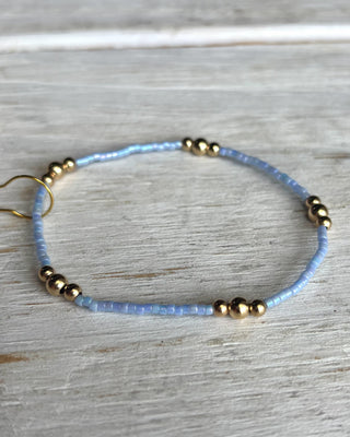 Blue beaded bracelet with gold beads on a light wooden surface