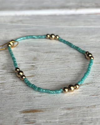 Turquoise beaded bracelet with gold accents on a wooden surface