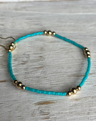 Turquoise beaded bracelet with gold beads on a wooden surface