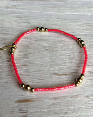 Bracelet with pink beads and gold accents on a wooden surface
