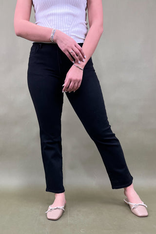 Person wearing black pants and a white top against a plain background