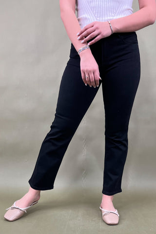 Person wearing black pants and a white top against a plain background