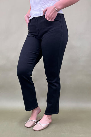 Person wearing black pants and a light blue top on a beige background