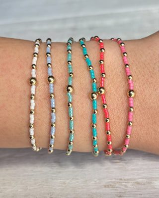 Set of beaded bracelets on a wrist with a neutral background