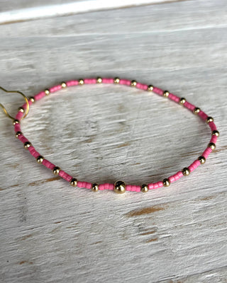 Necklace with pink and gold beads on a wooden surface