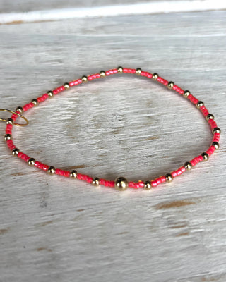 Necklace with pink and gold beads on a wooden surface