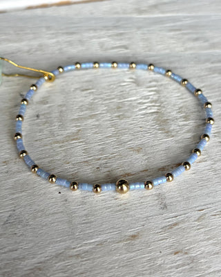 Beaded bracelet with gold and light blue beads on a wooden surface