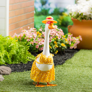 Decorative goose in a yellow raincoat and hat standing on grass with flowers and plants in the background.