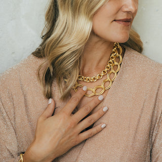 Woman wearing a gold chain necklace with a neutral background
