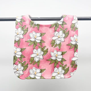 Pink fabric bib with white floral pattern on a white background