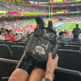 Person holding a phone with a stadium in the background
