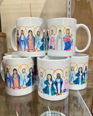 Set of four mugs with colorful illustrations on a reflective surface.