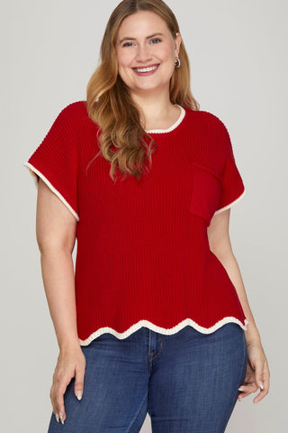 Woman wearing a red sweater with white trim on a plain background