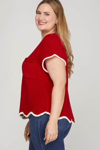 Woman wearing a red top with white trim on a plain background