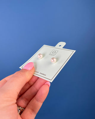 Enewton Classic Pearl Stud Earrings featuring luminous white faux pearls with 14kt gold-filled posts displayed on an Enewton