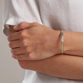 Gold bracelet on a person's wrist with a neutral background