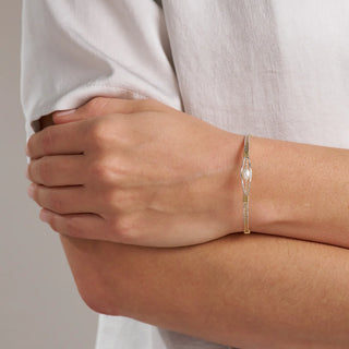 Person wearing a delicate gold bracelet on a neutral background