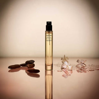 Perfume bottle with coffee beans and flowers on a reflective surface