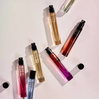Collection of perfume bottles with colorful liquids on a light background