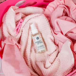 Bottle of 'sweet grace' stain remover on pink towels in a pink basket