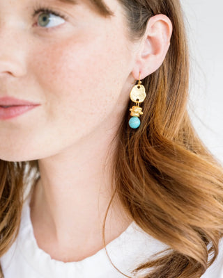 Gold and turquoise earrings on a Susan Shaw branded card against a pink background