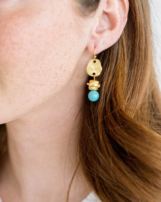 Gold and turquoise earrings on a Susan Shaw branded card against a pink background