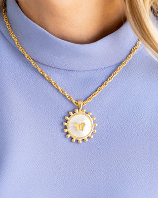 Gold necklace with a butterfly pendant on a light blue background