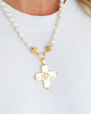 Pearl necklace with a gold cross pendant on a white background