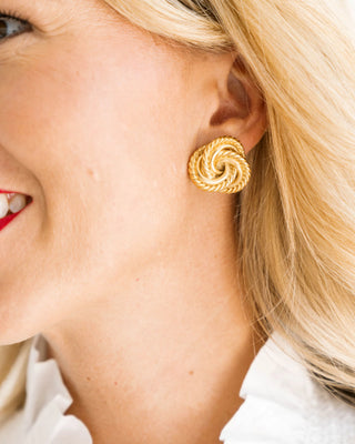 Close-up of a woman wearing gold spiral earrings.
