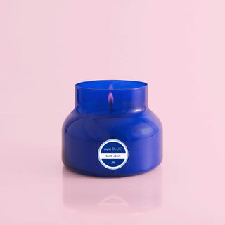Blue candle in a glass jar with a label on a pink background