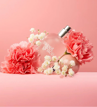 Perfume bottle labeled 'sweet grace' with pink and white flowers on a pink background