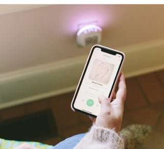 Person using a smartphone app to control a smart light bulb on a ceiling