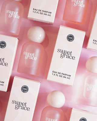 Sweet Grace perfume bottles and boxes on a pink background